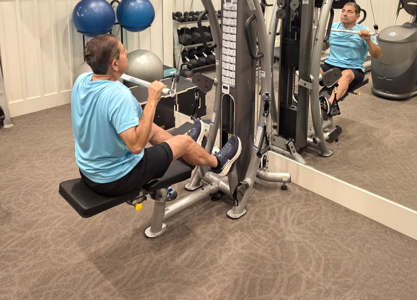 A man doing a seated cable row on a multi-gym in a home gym
