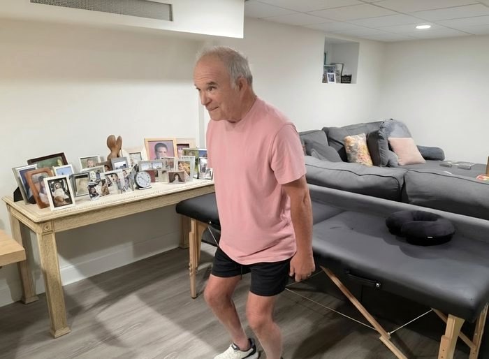 An older adult standing beside a portable treatment table during an in-home visit